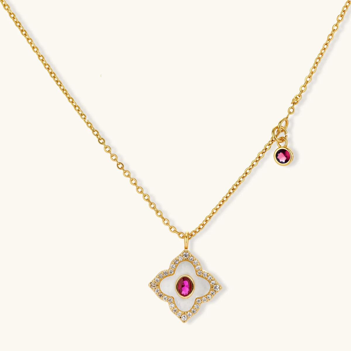 Gold-plated quatrefoil necklace and earring set with white enamel, pink cubic zirconia centers, and crystal borders