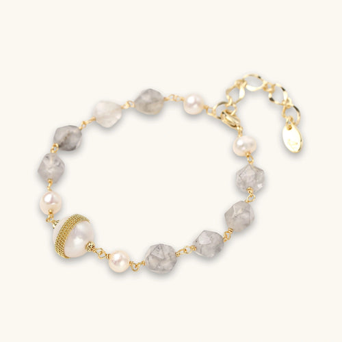 Bracelet with cloudy quartz beads, freshwater pearls, and gold-wrapped baroque pearl centerpiece on white background.